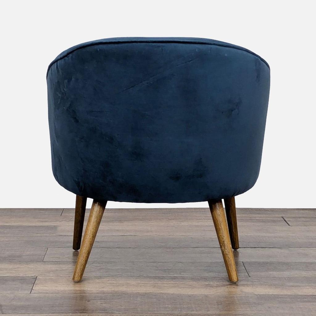 3. Rear view of West Elm lounge chair featuring blue velvet upholstery and angled wood legs.