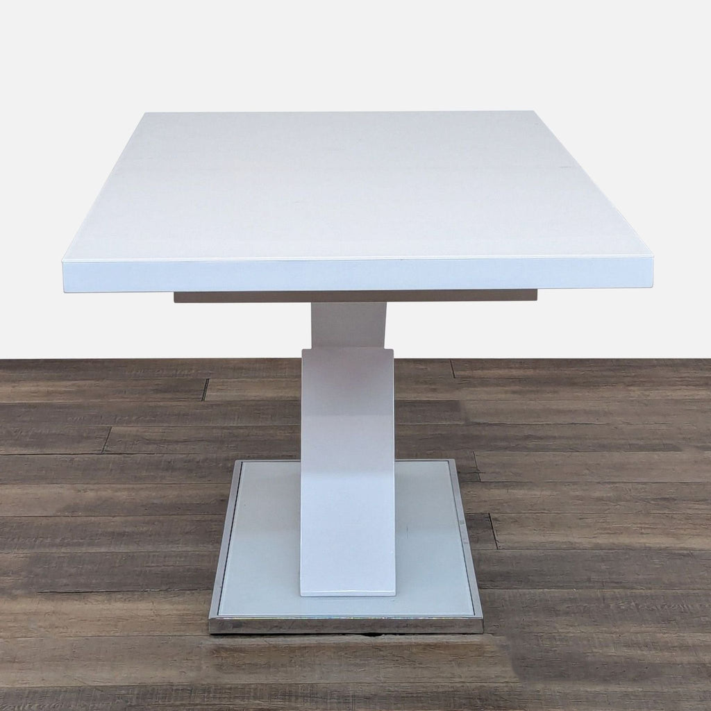 Side view of Reperch's white expandable dining table on wood floor, highlighting the sleek pedestal base.