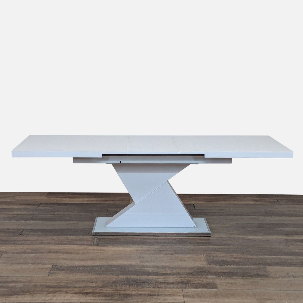 Expandable Reperch dining table with geometric pedestal base in white finish, shown without chairs.  