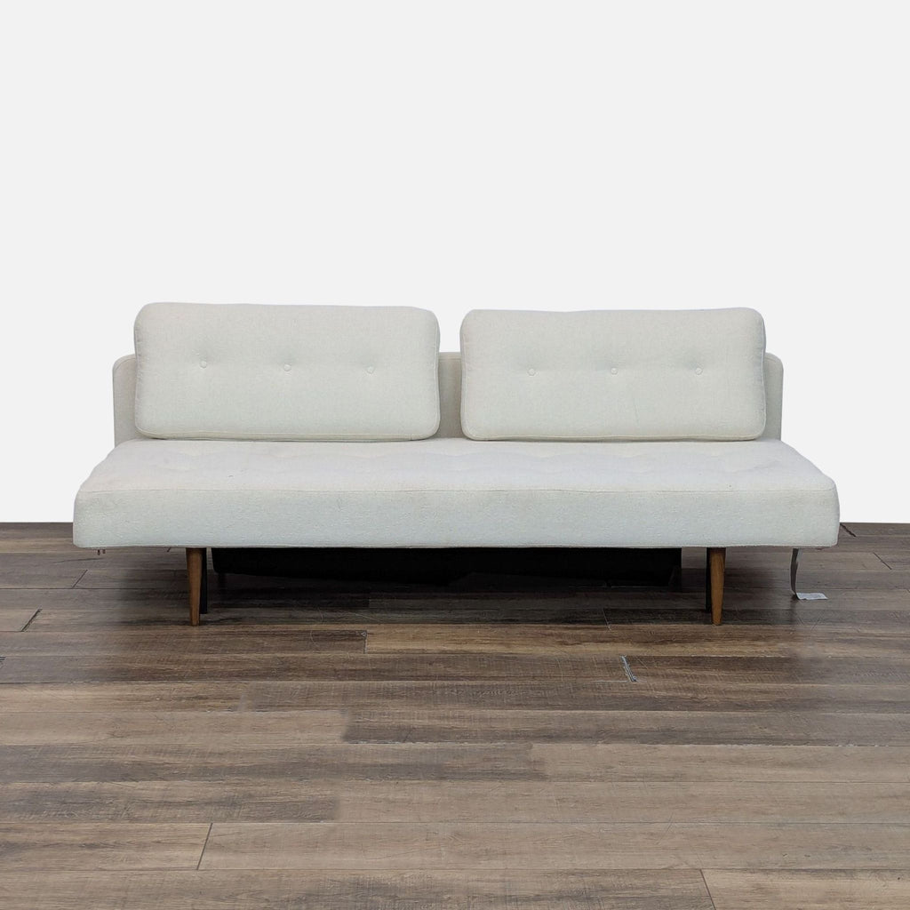 1. Modern Room & Board sleeper sofa with button tufting and under-seat storage on wooden floor.