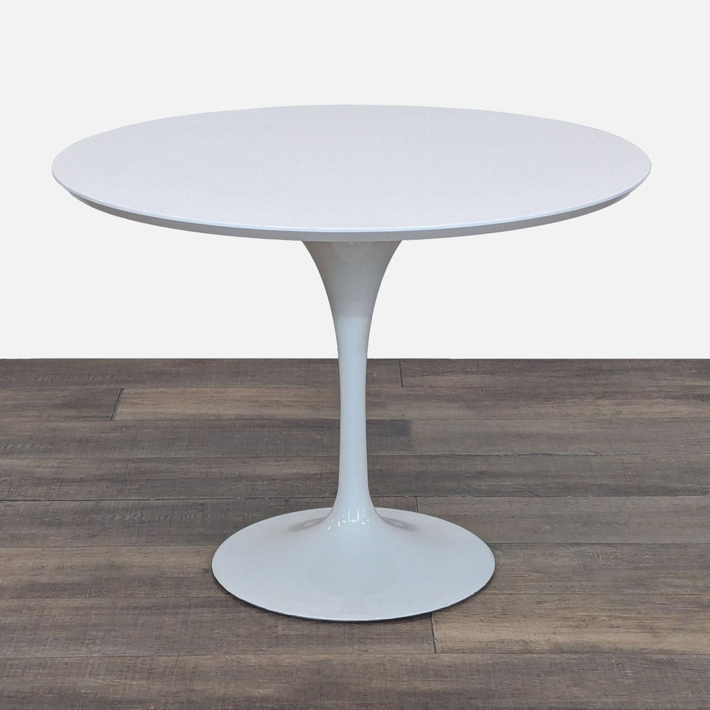 Sleek white round Reperch dining table with a modern tulip pedestal base, shown on a wood floor.