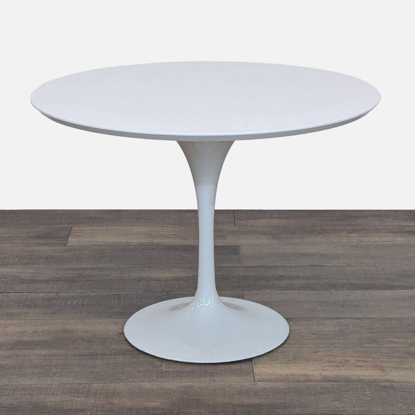 Sleek white round Reperch dining table with a modern tulip pedestal base, shown on a wood floor.