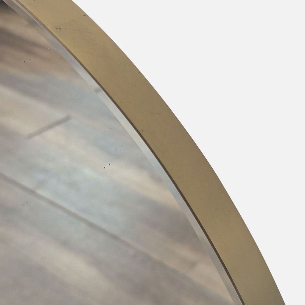 3. Close-up of the Crate and Barrel mirror’s gold-toned frame and reflective glass edge detail.