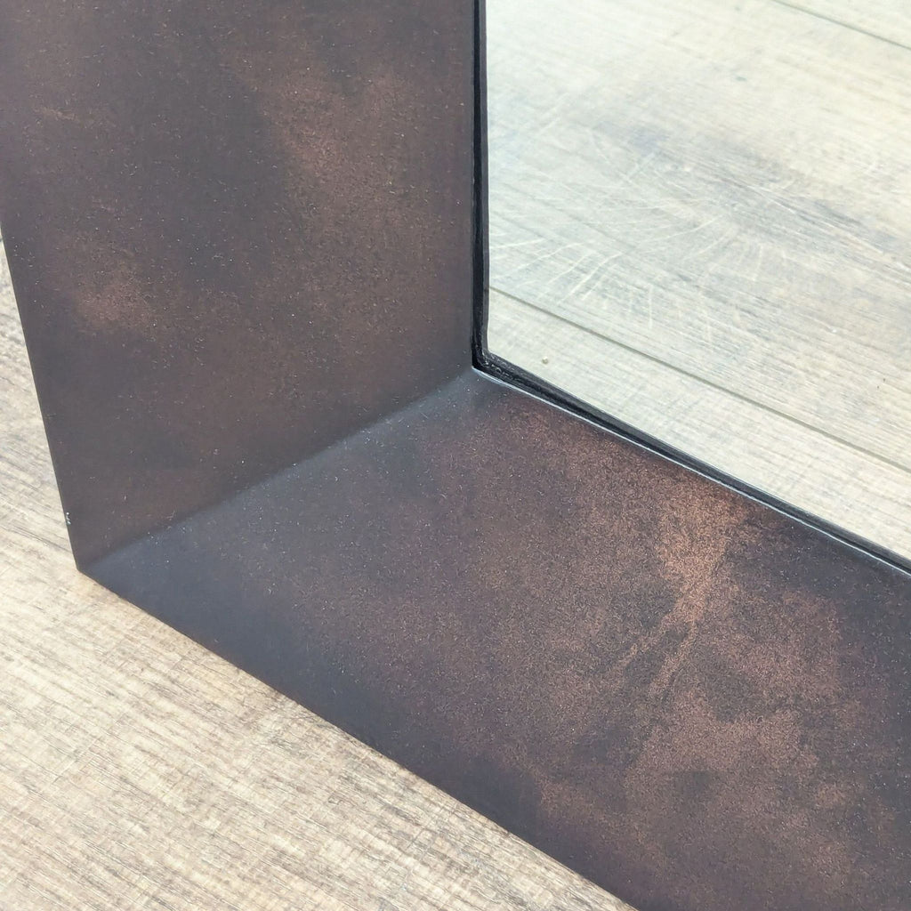 2. Close-up of Crate & Barrel mirror shows textured dark metallic frame corner next to square glass panel.