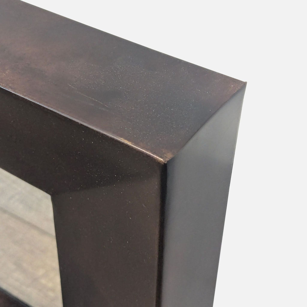 3. Angled view of Crate & Barrel mirror reveals deep, wide-edged metallic frame with smooth dark brown surface.