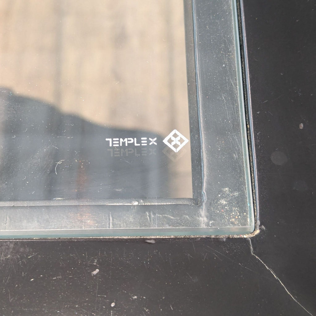 2. Close-up of the glass tabletop corner on Reperch dining table, showing TEMPLEX brand marking.  