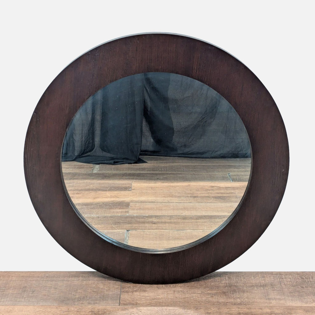 1. Round Crate and Barrel mirror with a wide, dark wood frame, displayed upright on a wood floor.
