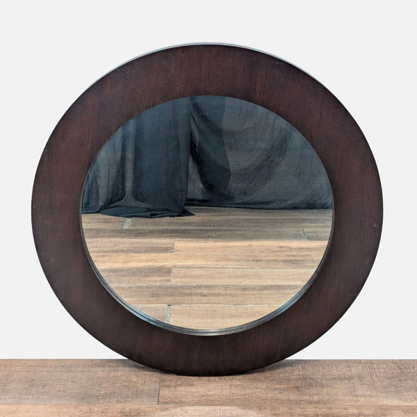 1. Round Crate and Barrel mirror with a wide, dark wood frame, displayed upright on a wood floor.