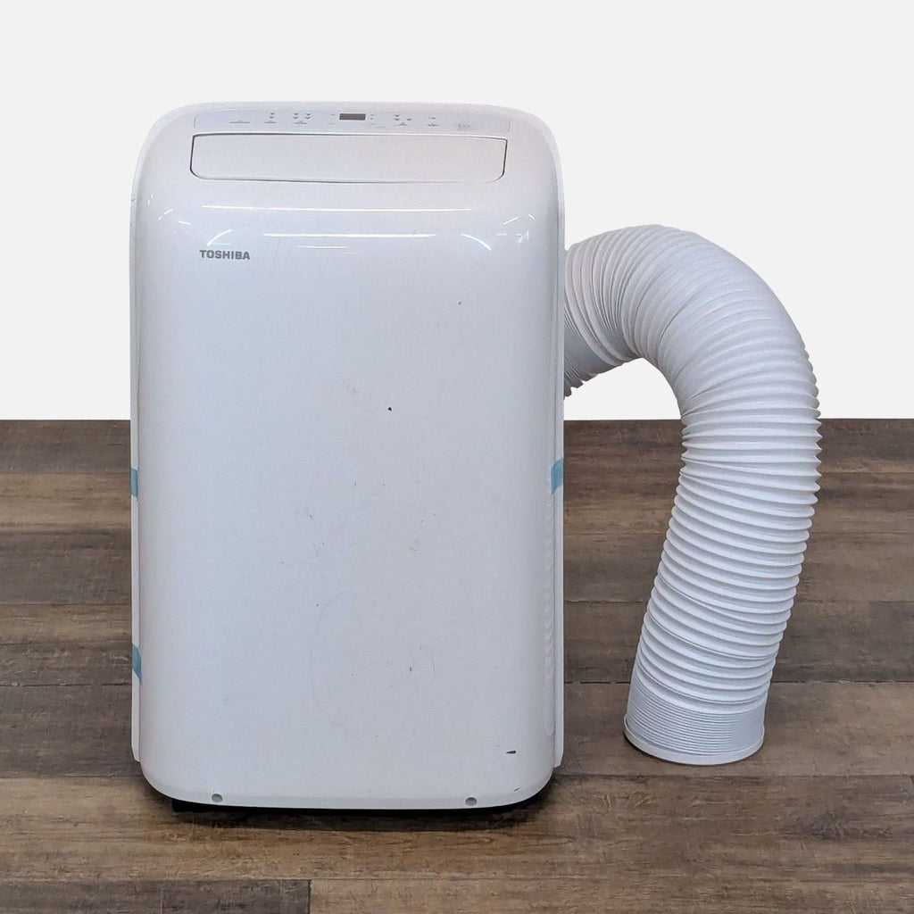 1. Front view of a Toshiba portable air conditioner with attached exhaust hose, designed for efficient room cooling.
