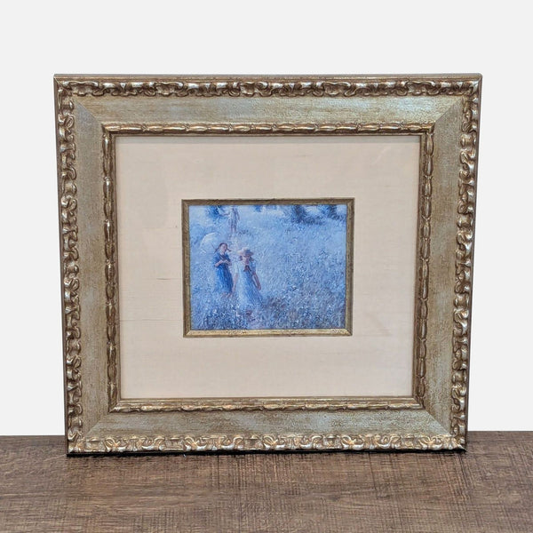 Art print showing children in a field, set in an ornate gold frame by Reperch, seen on a table.  