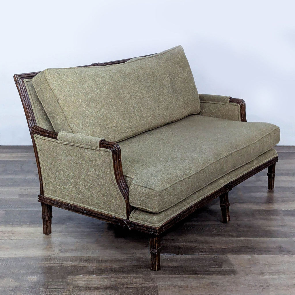 2. Angled view of Century loveseat showing textured green upholstery and intricate wooden arms and base.