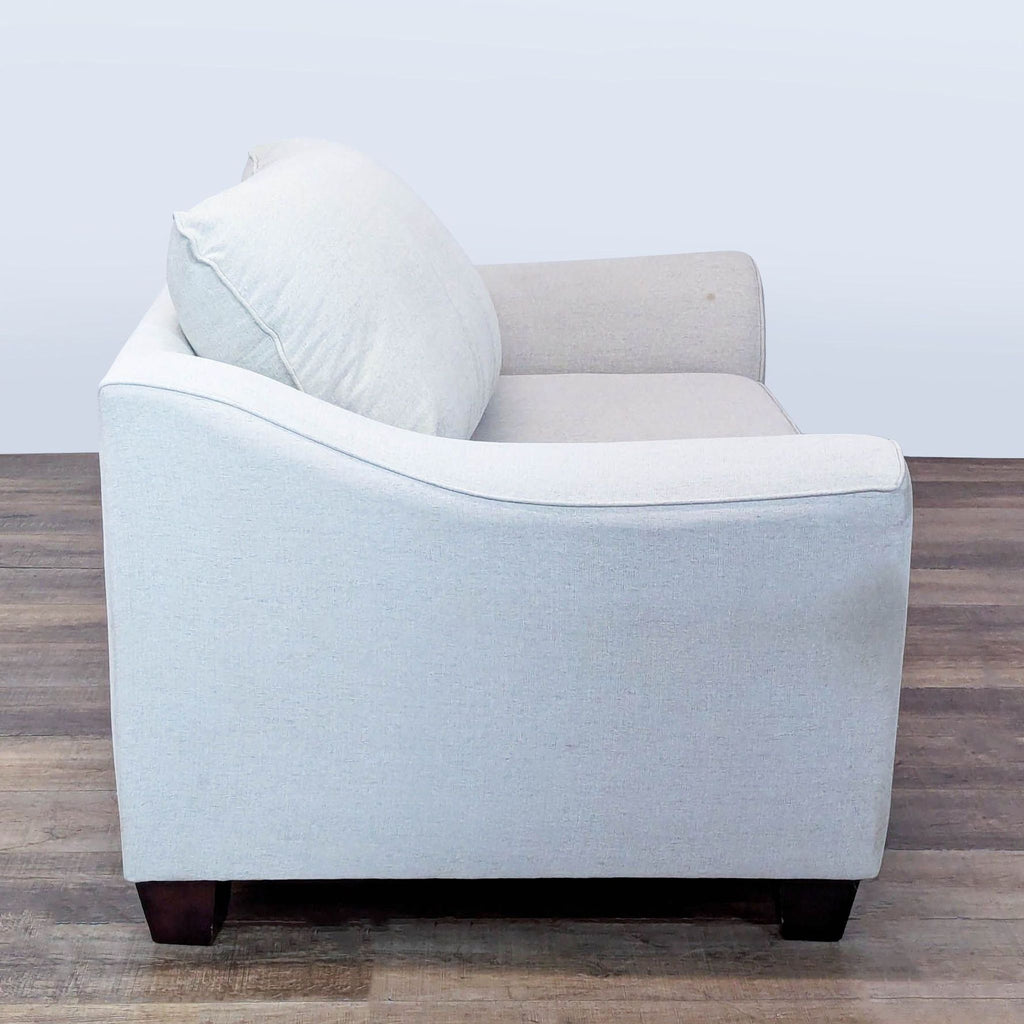 2. Side view of a Living Spaces lounge chair featuring plush cushions and sturdy wooden feet on wood flooring.