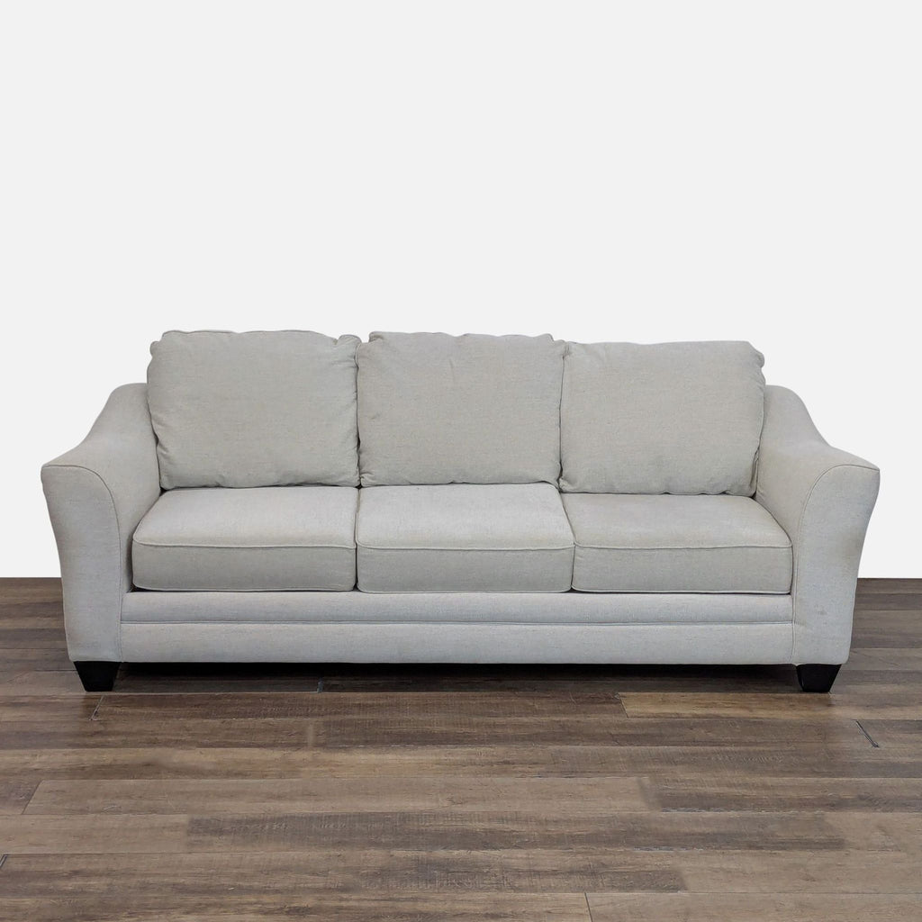 Front view of a light gray 3-seat Living Spaces sofa with three cushions and wood feet on a wooden floor.  