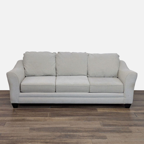Front view of a light gray 3-seat Living Spaces sofa with three cushions and wood feet on a wooden floor.  