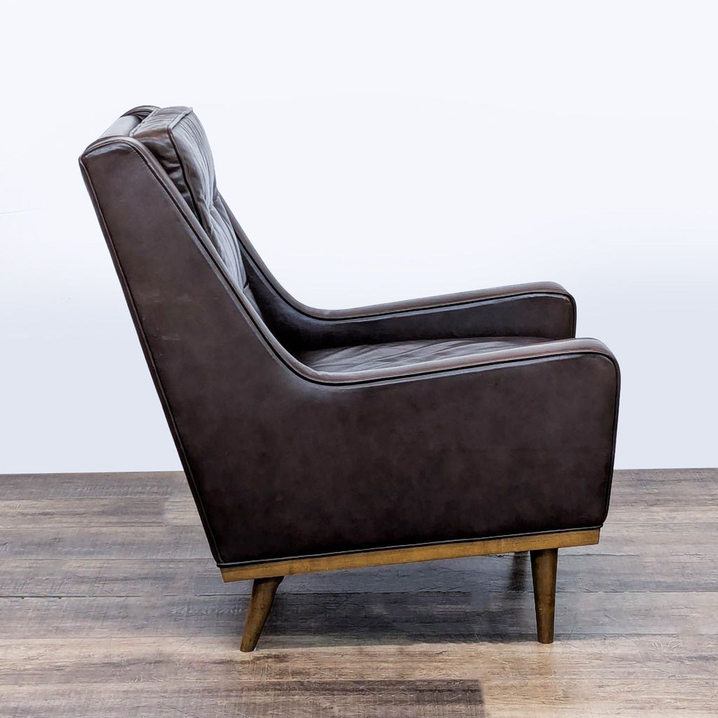 2. Side profile of a Reperch lounge chair featuring brown leather upholstery and angled conical wood legs.