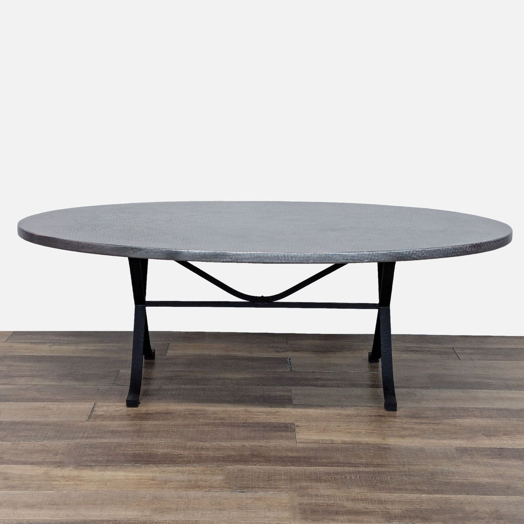 2. Oval dining table by Kravet Furniture featuring a textured metal top and black iron base, no chairs.