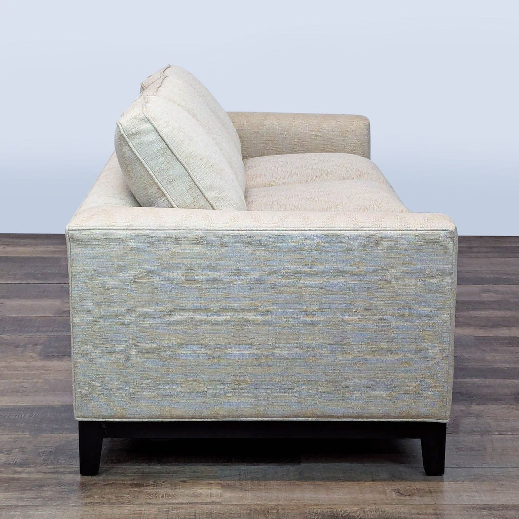 2. Side profile of a minimalist three-seat sofa, showing low arms and deep cushions in subtle patterned fabric.