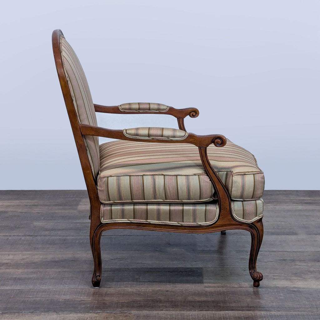 Side view of Ethan Allen lounge chair showcasing carved wood armrest and striped fabric.  