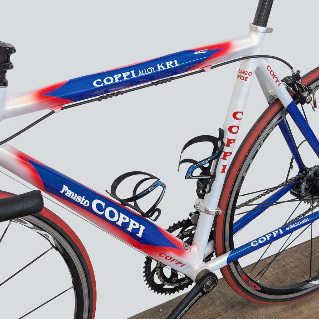 3. Close-up of the Coppi racing bike frame, showing carbon fiber parts, bottle cages, and distinctive red, blue, and white design.
