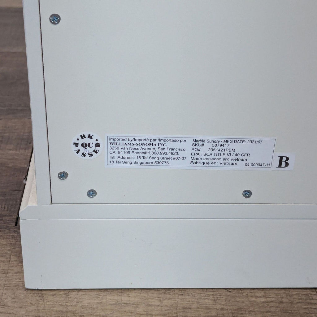 Close-up of the product label on the back of a Pottery Barn end table with manufacturing and import details.