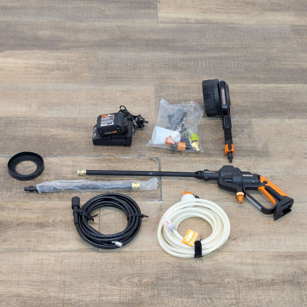 Worx WG620 Hydroshot power cleaner kit with battery, hoses, attachments, and brush on a wooden surface.  