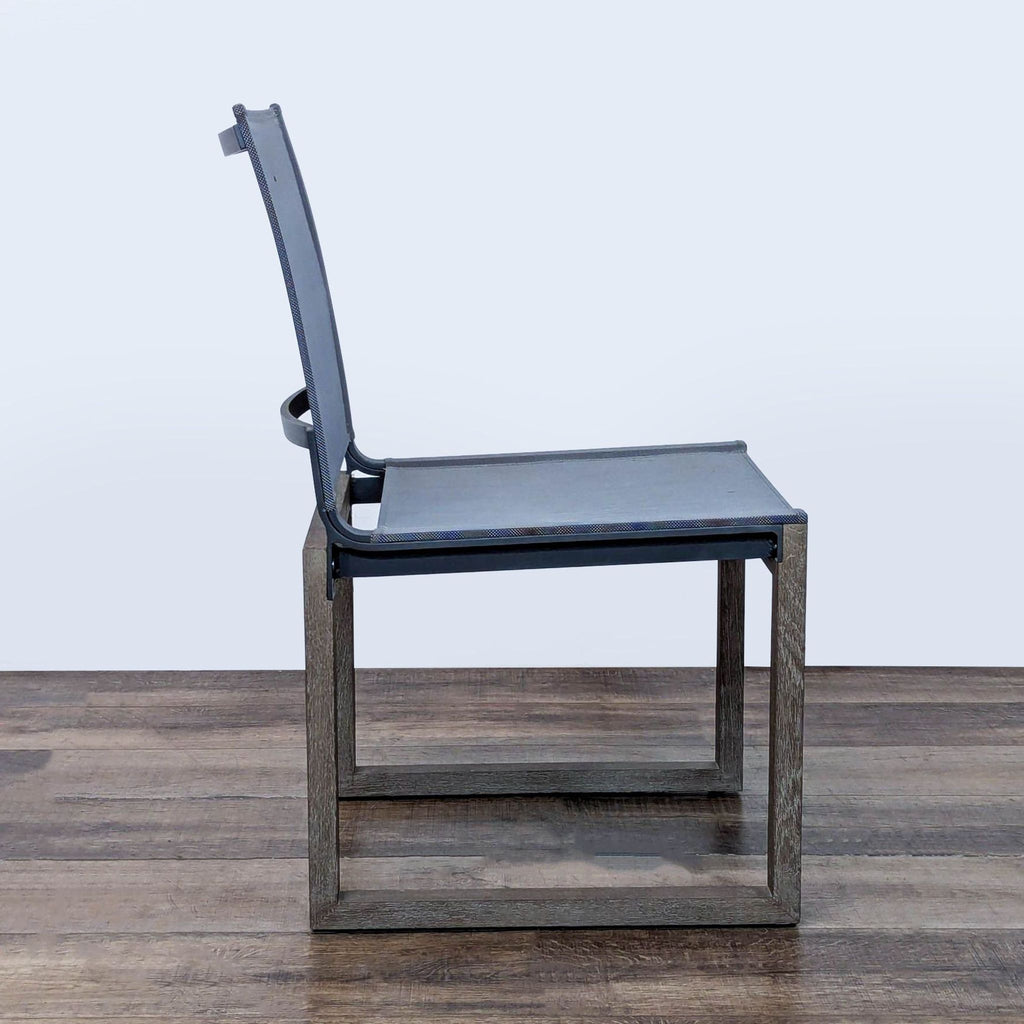 2. Side profile of Restoration Hardware's Aegean outdoor chair, featuring a teak frame and charcoal mesh seat and back.