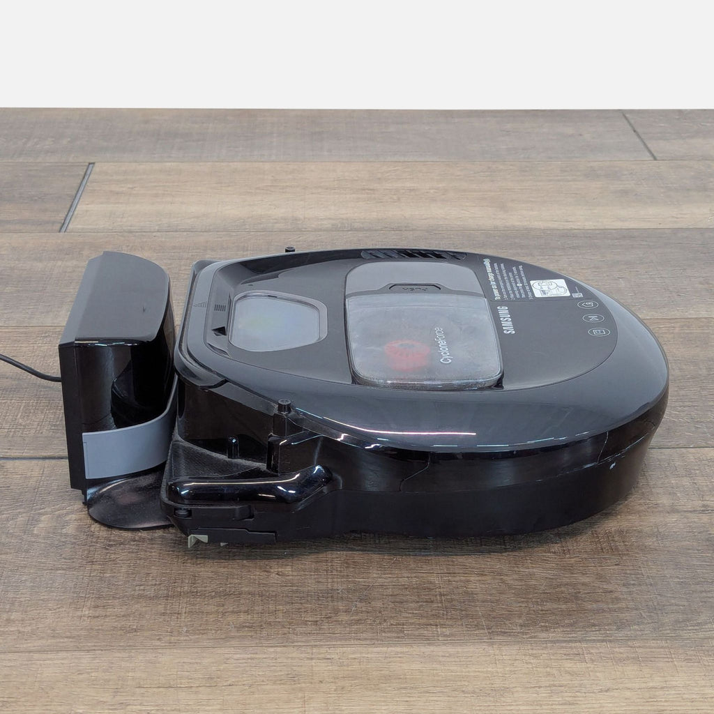 3. Side view of the Samsung POWERbot robot vacuum and charger dock, showcasing its low-profile, sleek gray design.