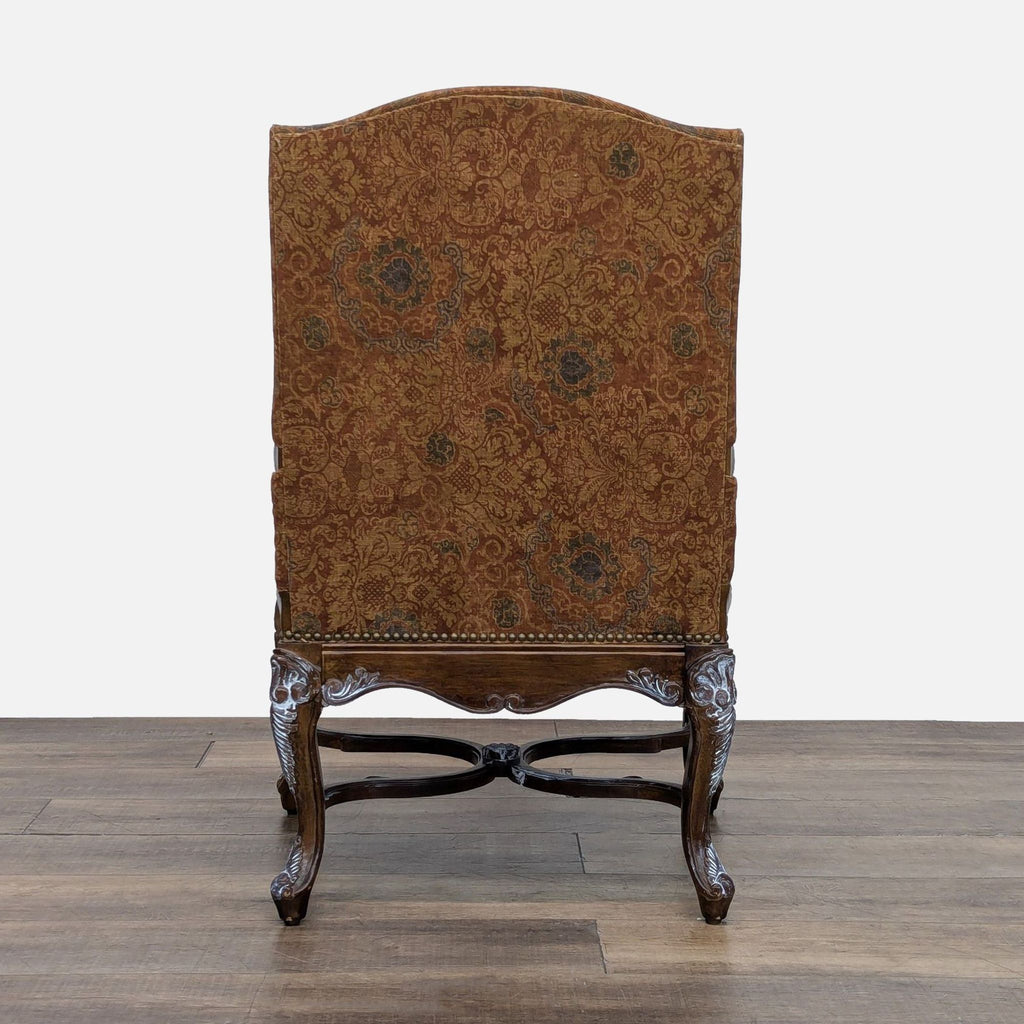 Back view of an Elegant Clutter lounge chair, upholstered with ornate patterns and detailed whitewashed carved wood frame.