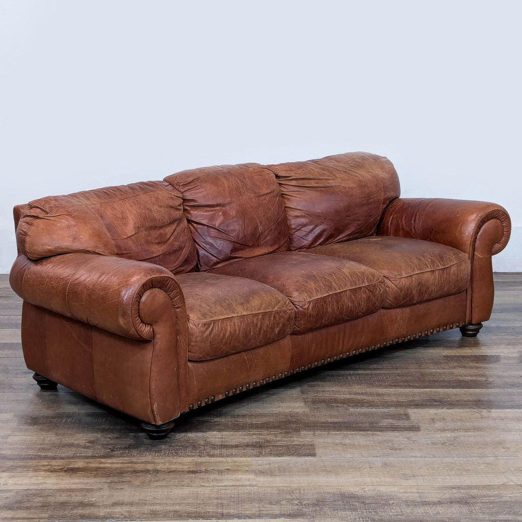 3. Angled view of Reperch brown leather 3-seater, showing rolled arms and plush, comfy cushions.