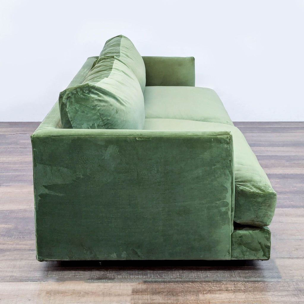 Side angle of West Elm Haven green velvet 3-seat sofa, highlighting its low arms and plush cushioning.