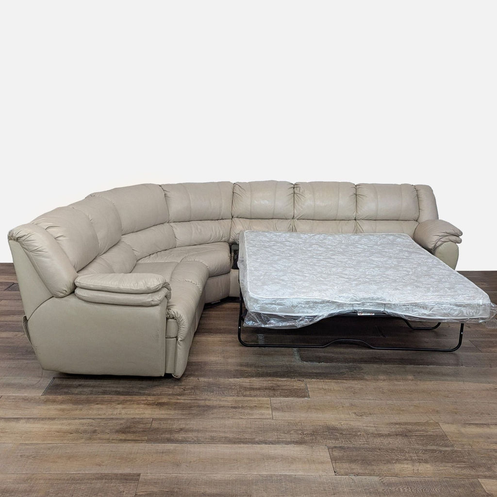 2. Ashley leather sectional with an open pull-out sleeper bed, offering both seating and extra sleeping space.