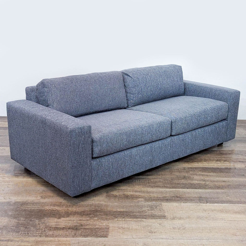 3. Angled side view of the West Elm sleeper sofa showing its track arms and plush blue cushions.
