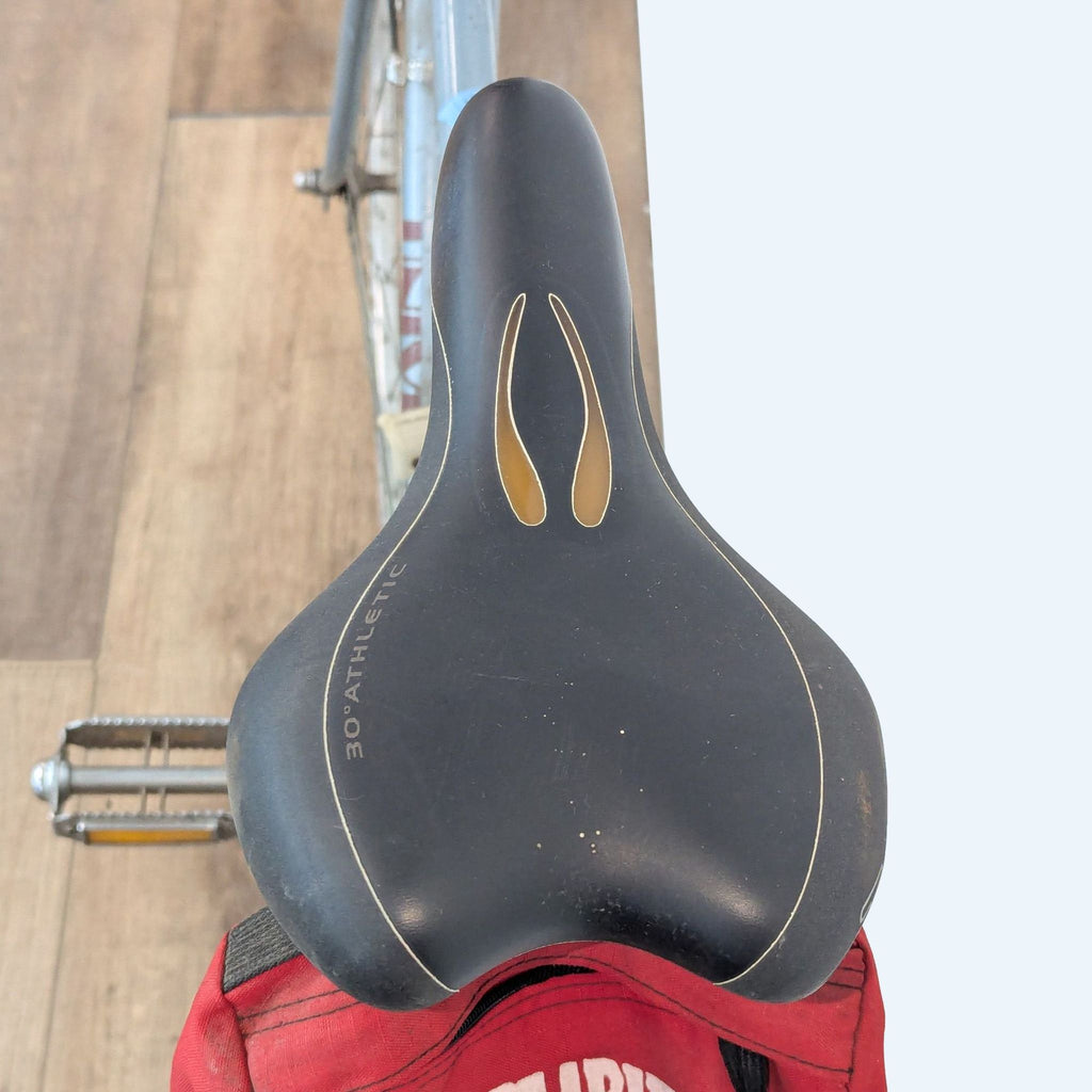 Close-up of the Univega road bike’s black saddle, labeled “30° Athletic,” with a red storage pouch underneath.