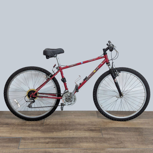 Red Schwinn mountain bike with sturdy frame, ergonomic seat, and reliable tires on a wooden floor background.  