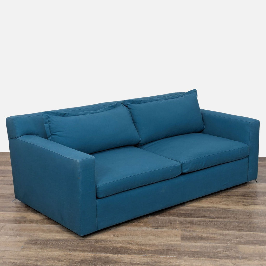 3. Angled side view of blue Anthropologie sofa, featuring plush, low-profile seat and t-shaped cushions.