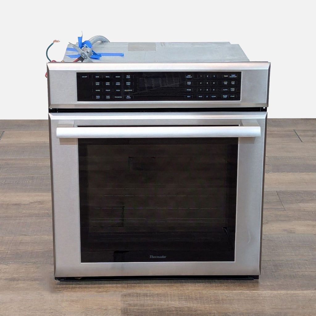 1. Front view of a Thermador ME271ES 27" stainless steel built-in microwave with digital controls and handle.