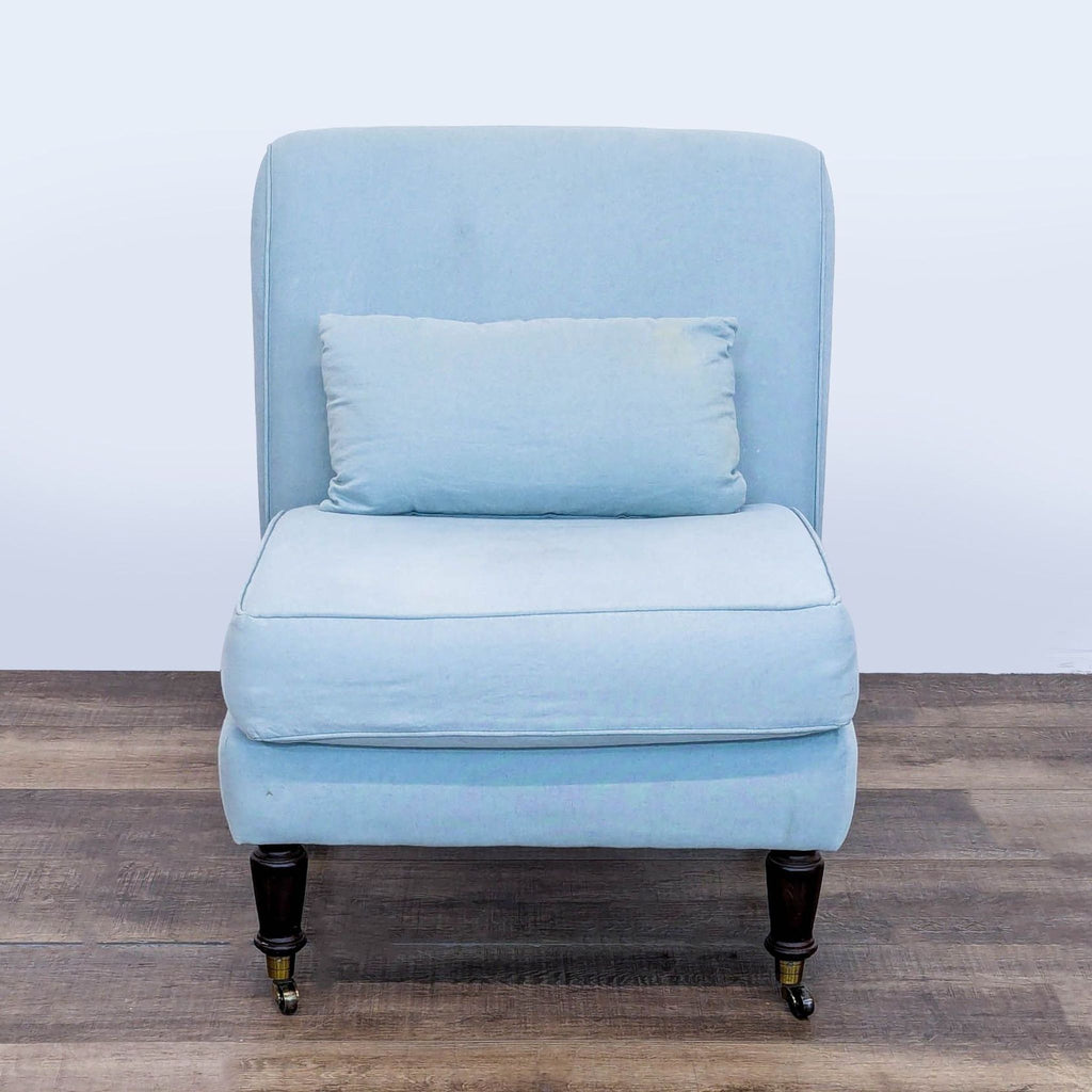 Front view of a Ballenger lounge chair with rolled back, blue fabric upholstery, and wood legs with brass casters.  