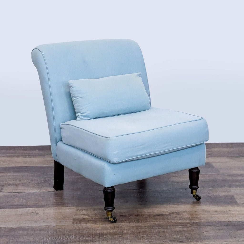 Three-quarter view of Ballenger lounge chair showcasing blue upholstery, rolled back, and wooden legs with brass casters.