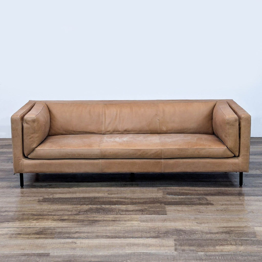 1. Arhaus Malta 3-seat sofa in brown leather with bench seats, bolster pillows, and rustic iron legs, front view.