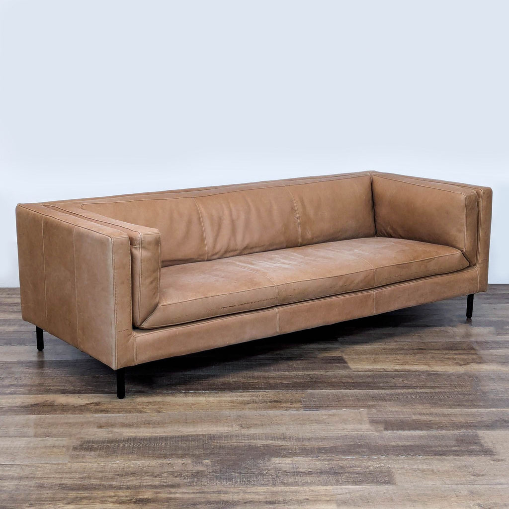 3. Angled view of Malta by Arhaus, a leather 3-seat sofa with clean lines, bolster pillows, and iron legs.