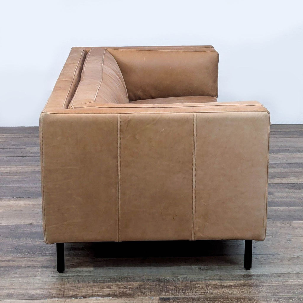 2. Side view of Arhaus Malta leather 3-seat sofa showing wide armrest, plush cushioning, and iron legs.