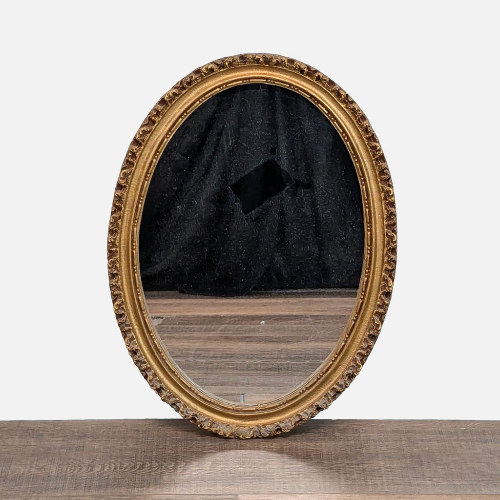 1. Oval Art Light Company mirror with ornate gold frame, displayed standing on a wooden surface.