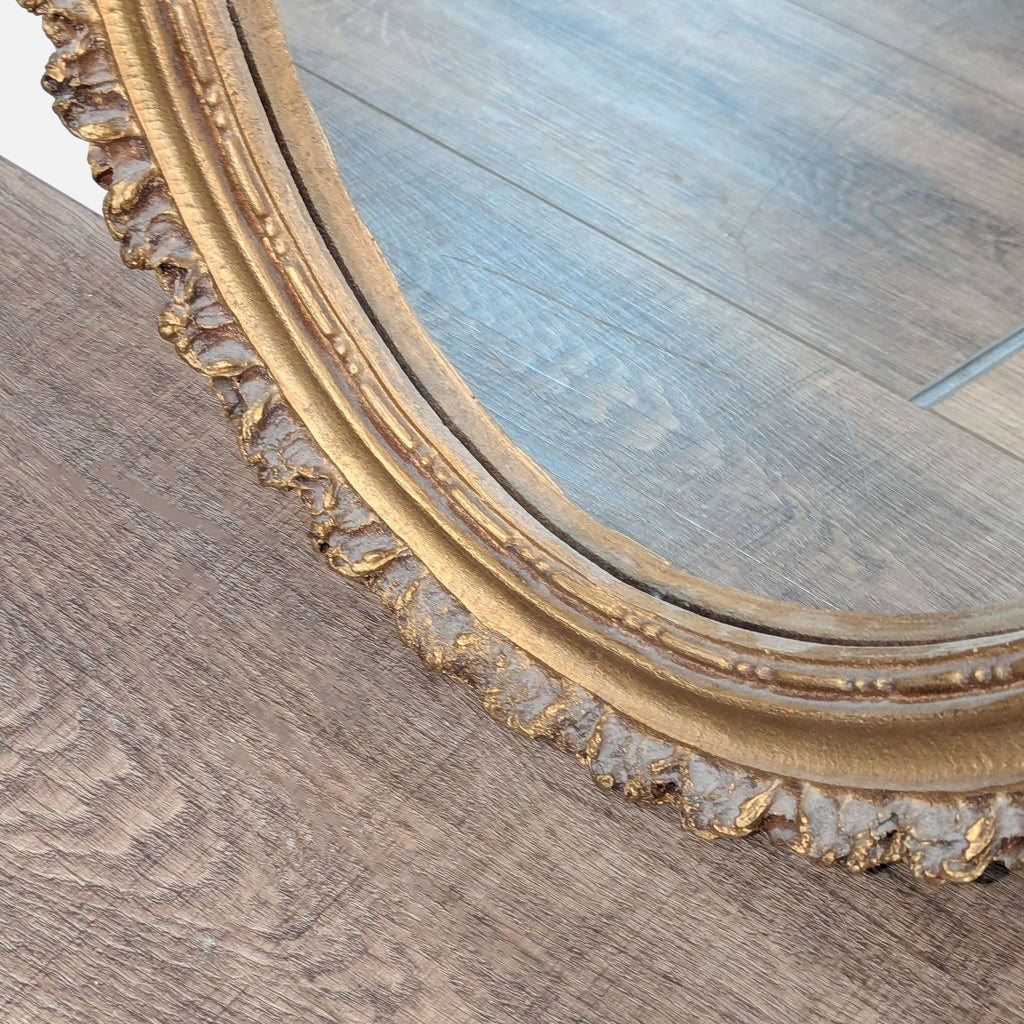 2. Close-up of the golden decorative frame on an Art Light Company oval mirror, showing its textured detailing.