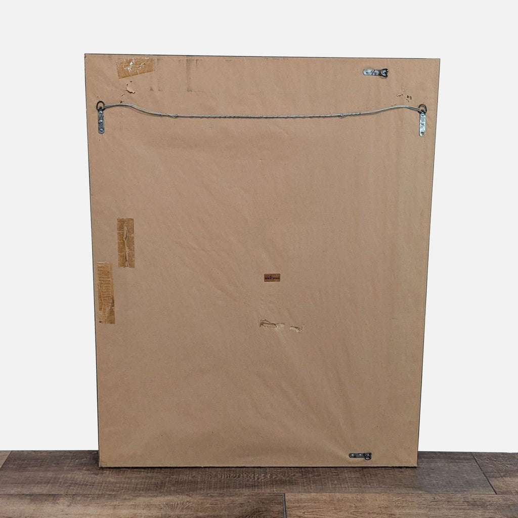 2. Back view of a Tobi Designs mirror, featuring a plain brown backing with a hanging wire and mounting hardware.