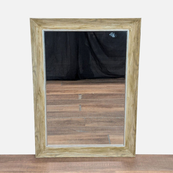 1. Rectangular Reperch mirror with a wide light wood frame, reflecting wooden flooring and a black backdrop.
