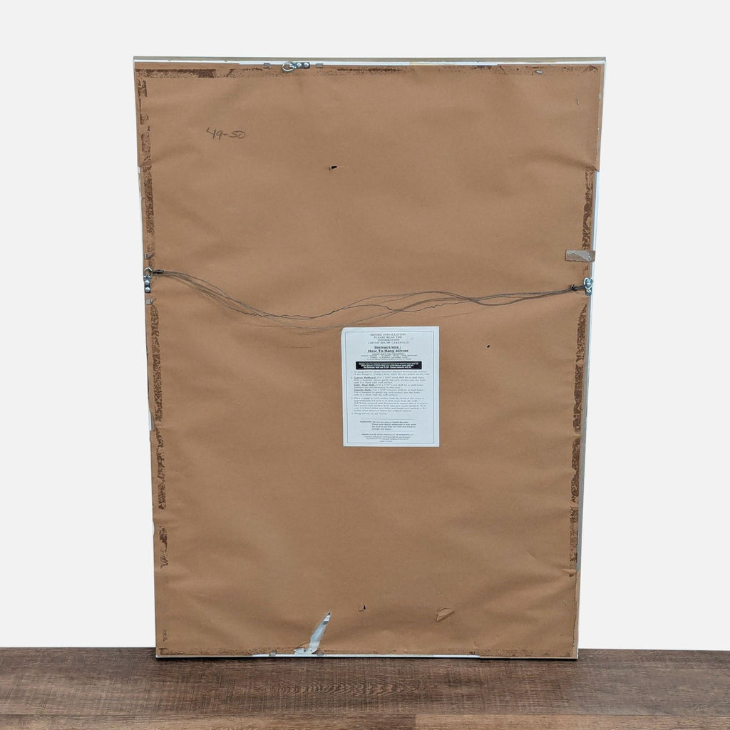2. Back view of the Reperch mirror showing brown paper backing, hanging wire, and a centered instruction label.