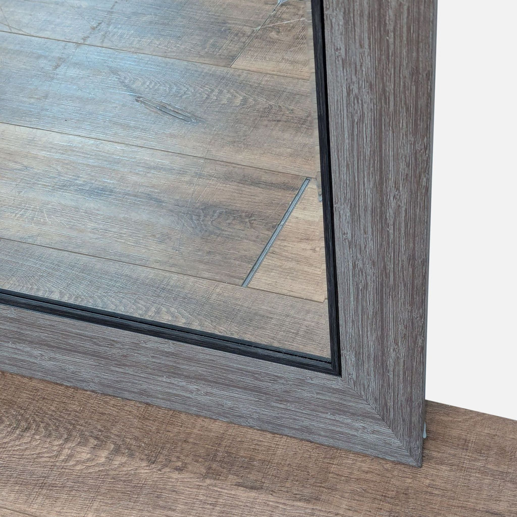 2. Close-up of the Reperch mirror’s textured wood-like frame and its reflection of the wooden floor.  