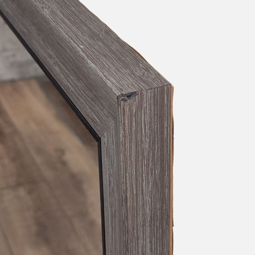 3. Angled detail of the Reperch mirror’s thick wood-textured corner frame, showing its construction.