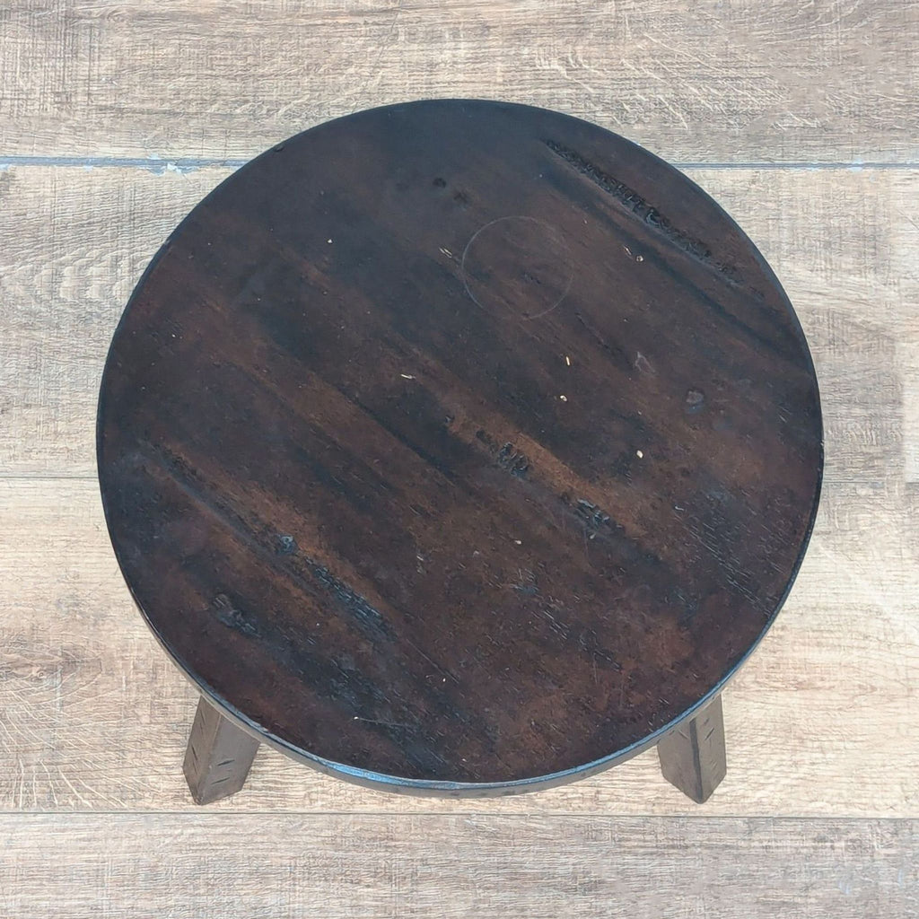 Top-down view of a Reperch round stool, showing a dark wood finish with visible natural grain.  
