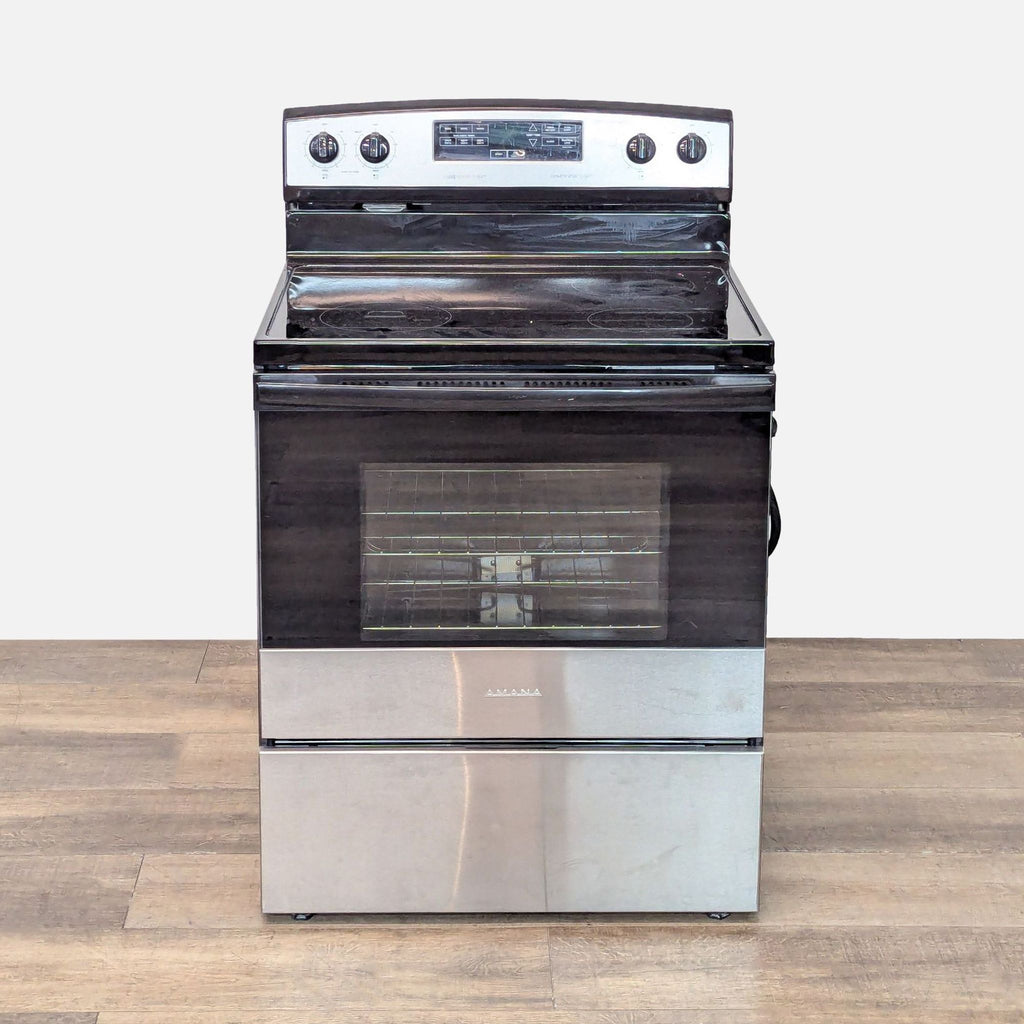 1. Front view of an Amana stainless steel electric stove and oven with four burners and clear oven door.